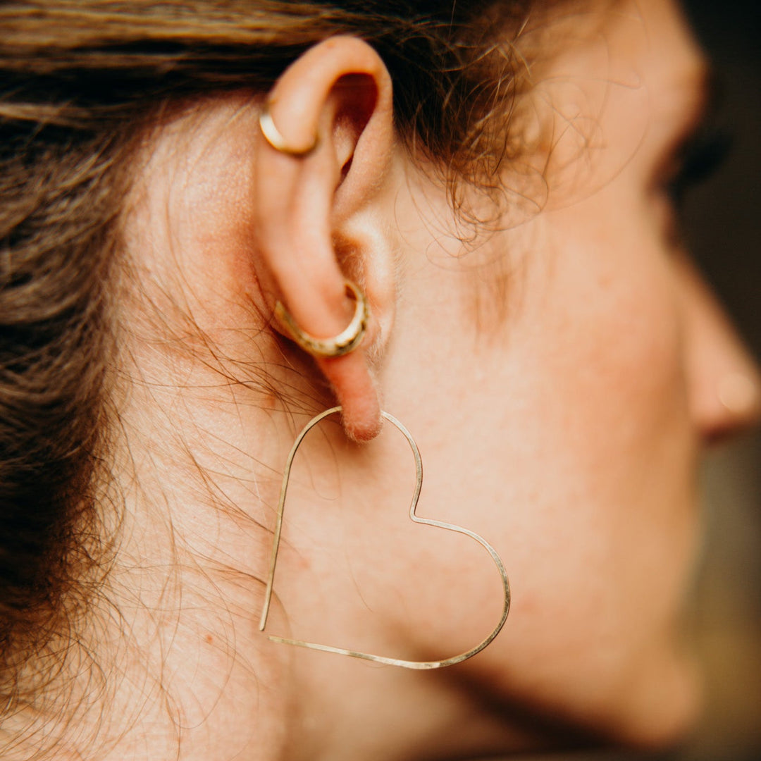 Close-up of a person wearing a heart-shaped earring with a blurred background