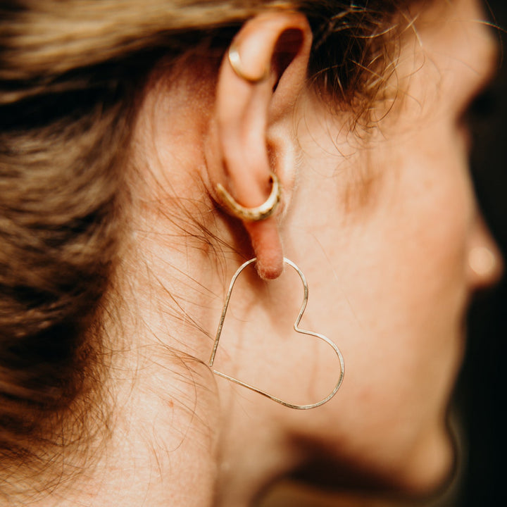 Close-up of a person wearing a heart-shaped earring with a blurred background