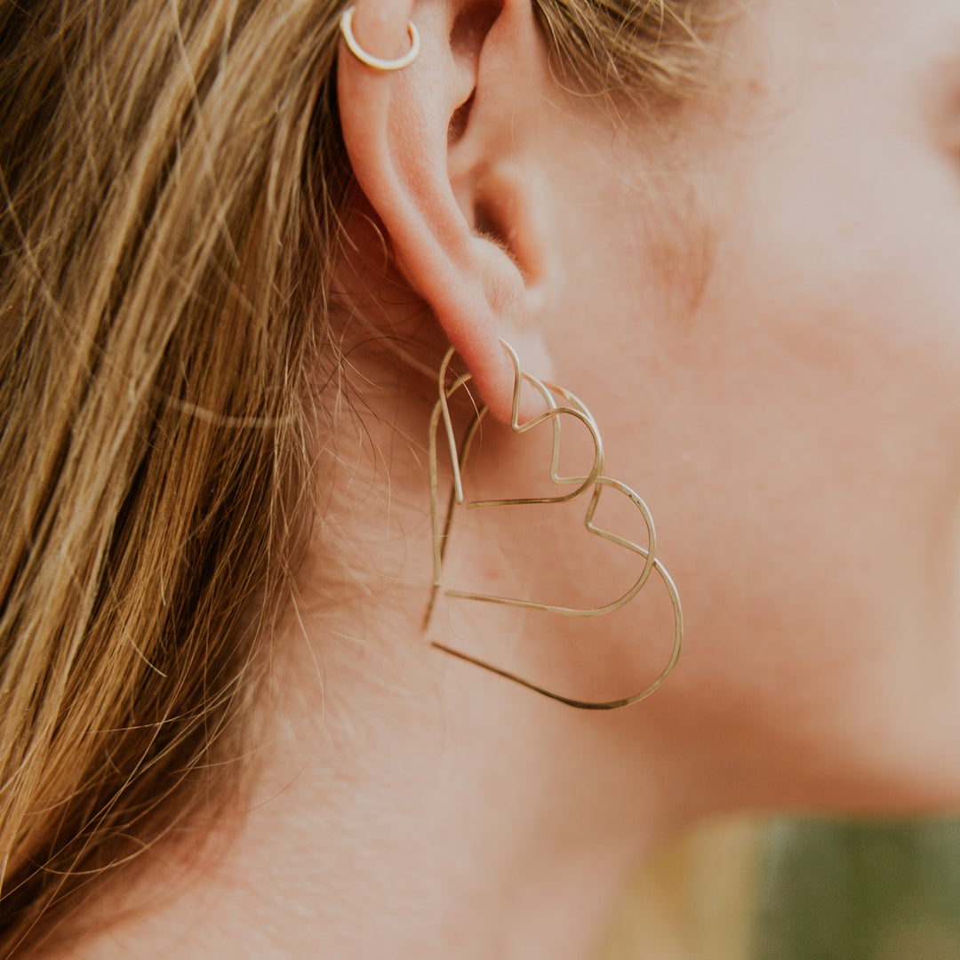 Close-up of a person wearing gold hoop earrings with blurred background