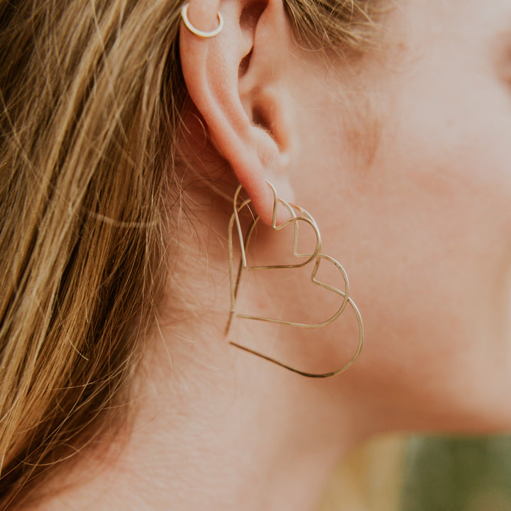 Close-up of a person wearing gold hoop earrings with blurred background