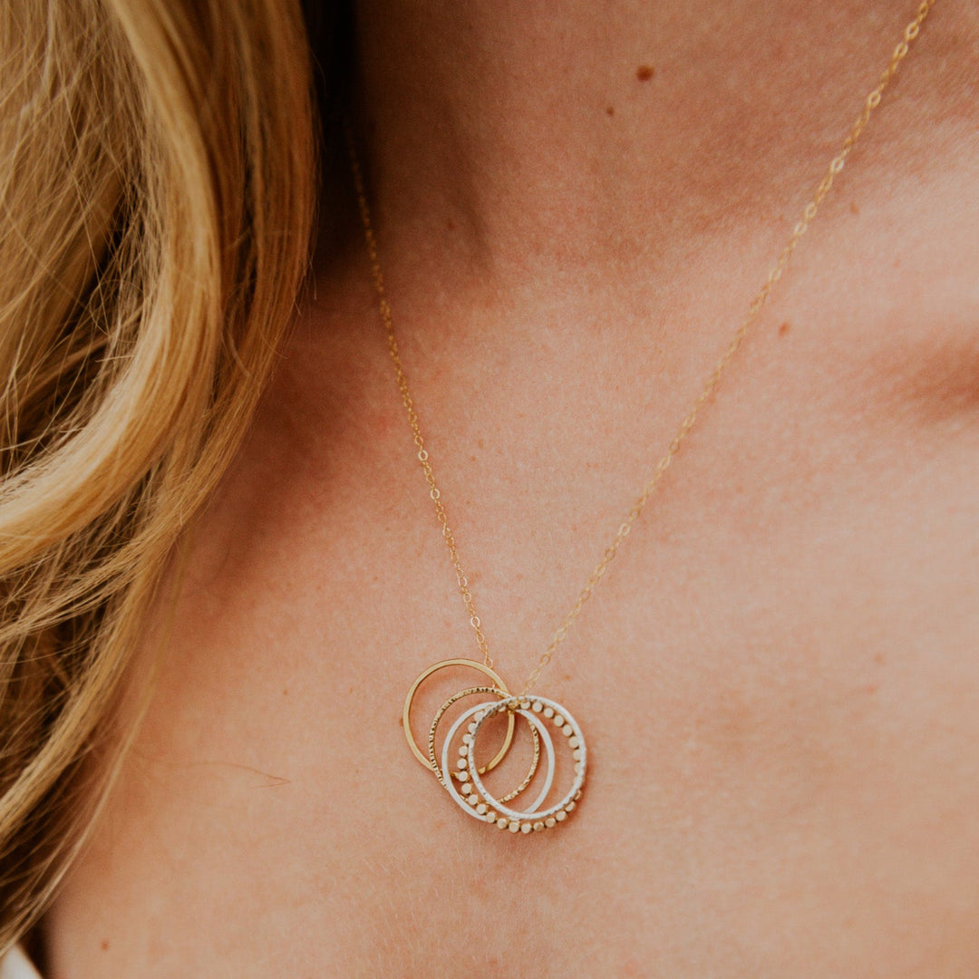 Gold necklace with circular pendants on a person's neck
