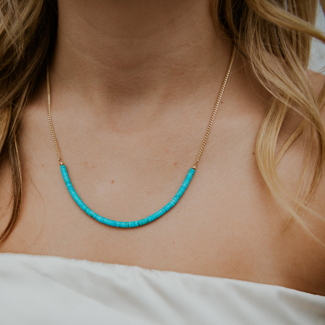 Necklace with turquoise beads worn by a person with blonde hair.
