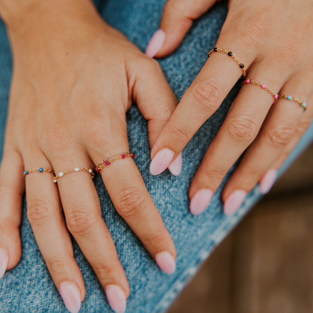Close-up of hands wearing colorful rings on a denim background