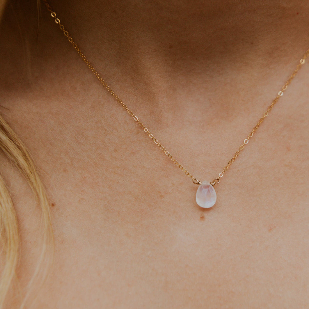 Gold necklace with a pink gemstone on a person's neck