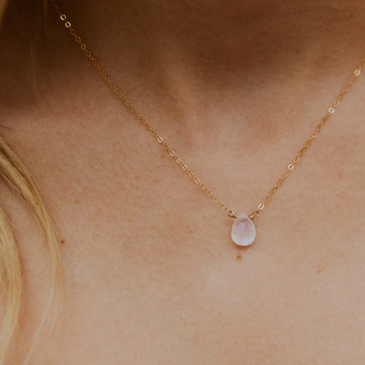 Gold necklace with a pink gemstone on a person's neck
