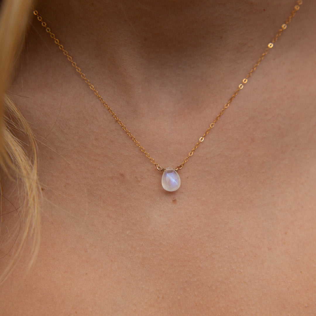 Gold necklace with a pendant on a person's neck