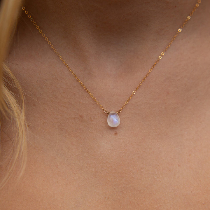 Gold necklace with a pendant on a person's neck