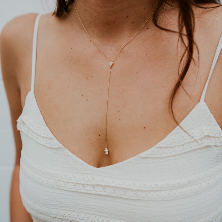 Woman wearing a delicate gold necklace with small beads, blurred background