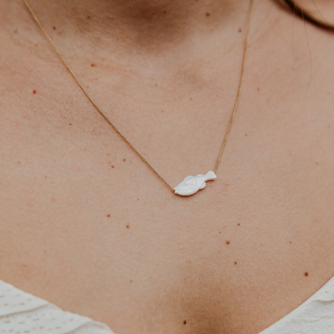 Necklace with a small pendant on a person's neck against a blurred background
