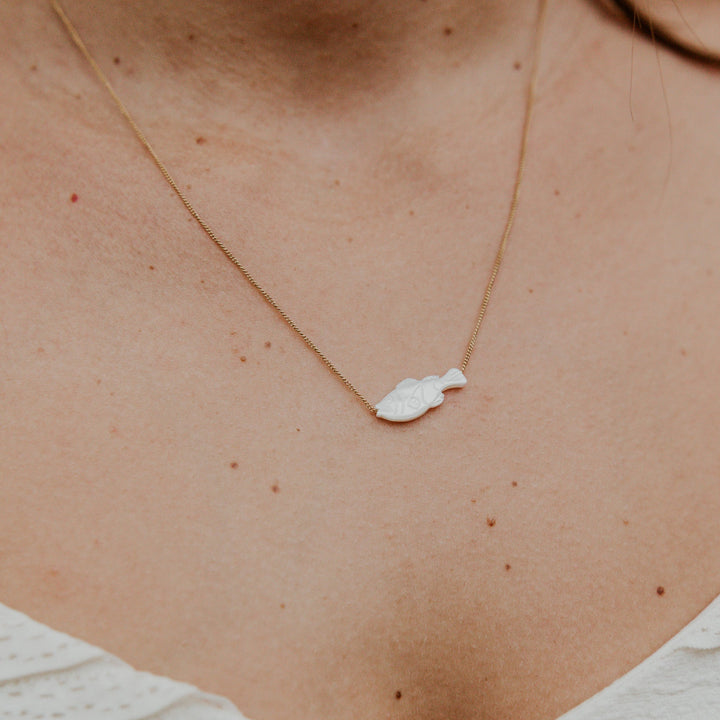 Necklace with a small pendant on a person's neck against a blurred background