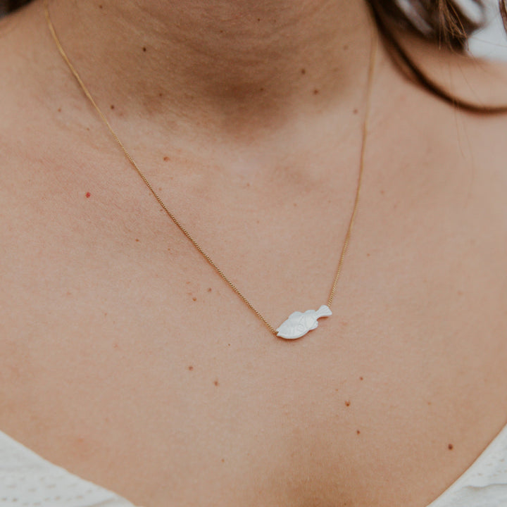 Necklace with a leaf-shaped pendant on a person's neck