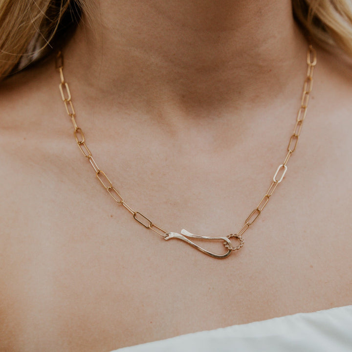 Gold chain necklace with a unique clasp on a person's neck