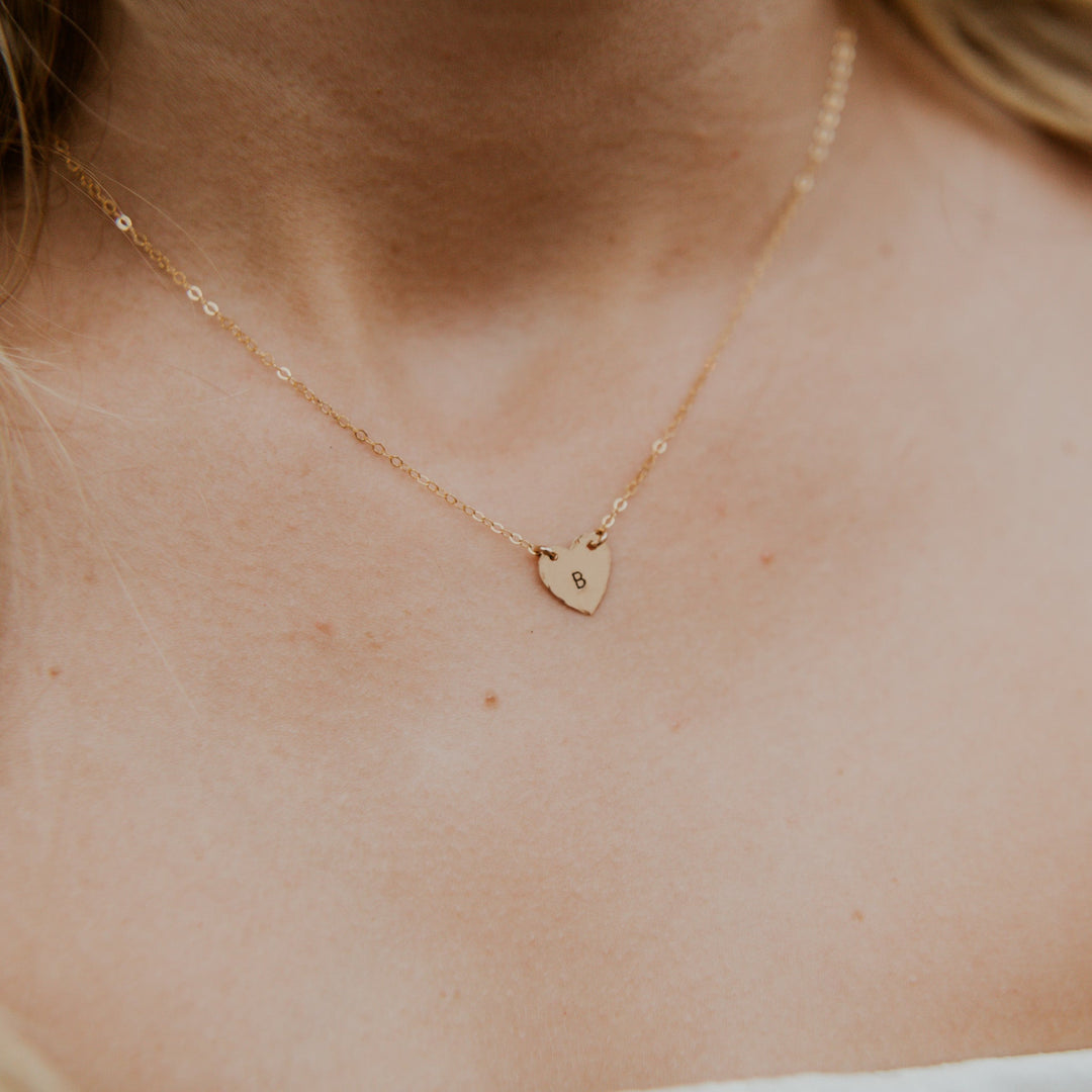 Gold heart-shaped necklace on a person's neck
