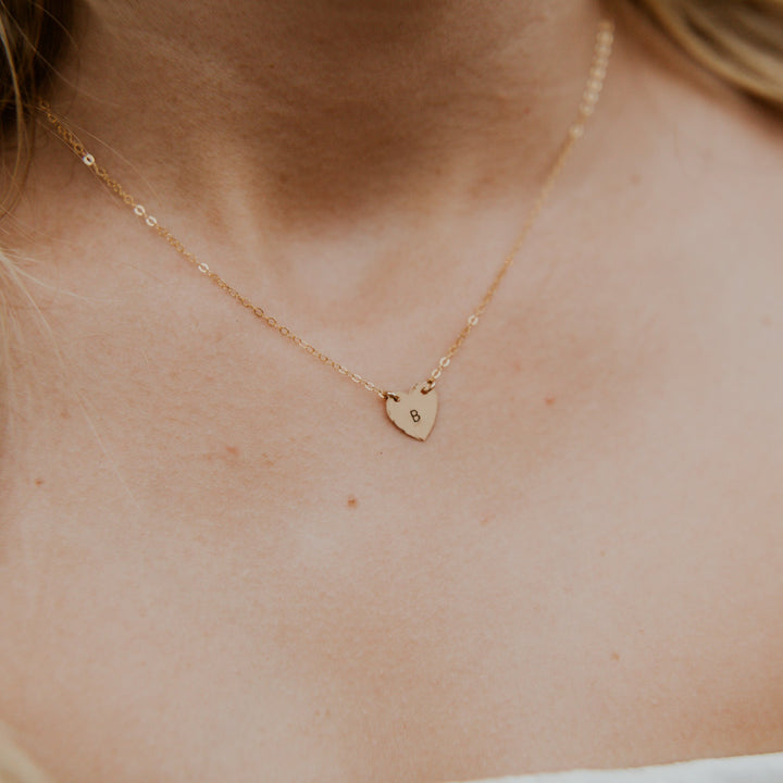 Gold heart-shaped necklace on a person's neck