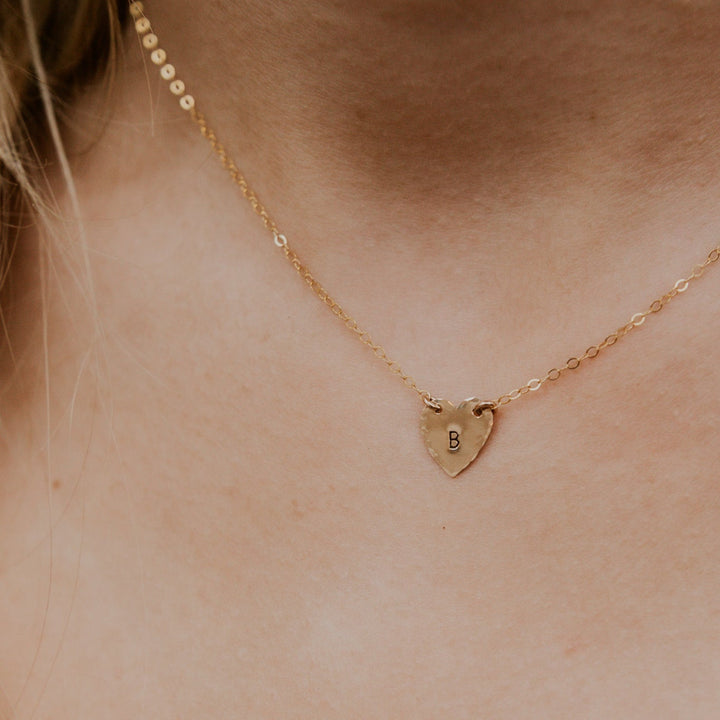 Gold necklace with a heart-shaped pendant on a person's neck