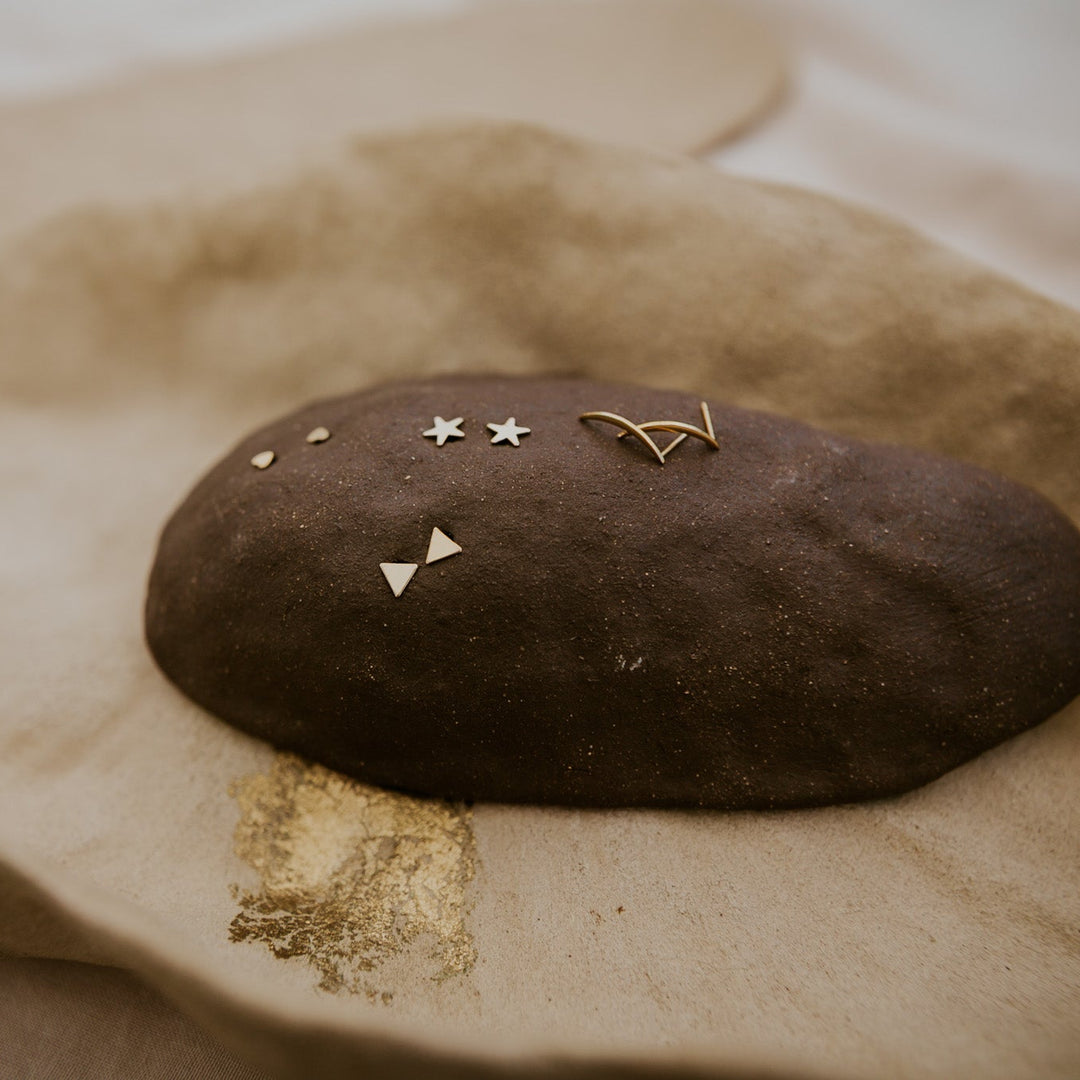 Decorative stone with small gold items on a beige surface