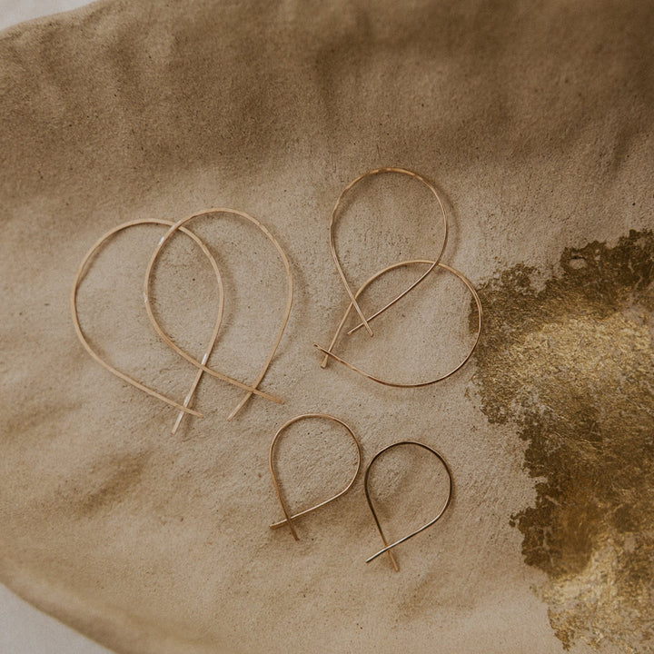 Set of gold earrings on a textured brown surface
