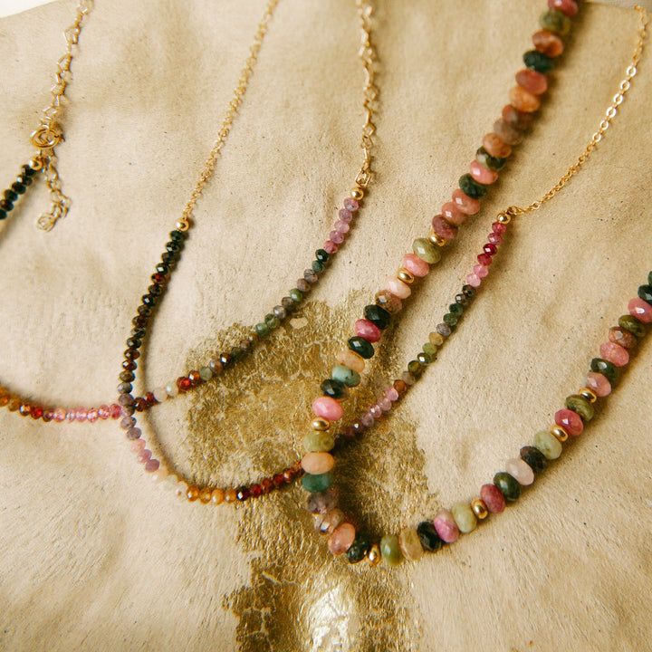 Flat lay of Aurora Necklace designs featuring genuine multi-color spinel on gold-filled chains.