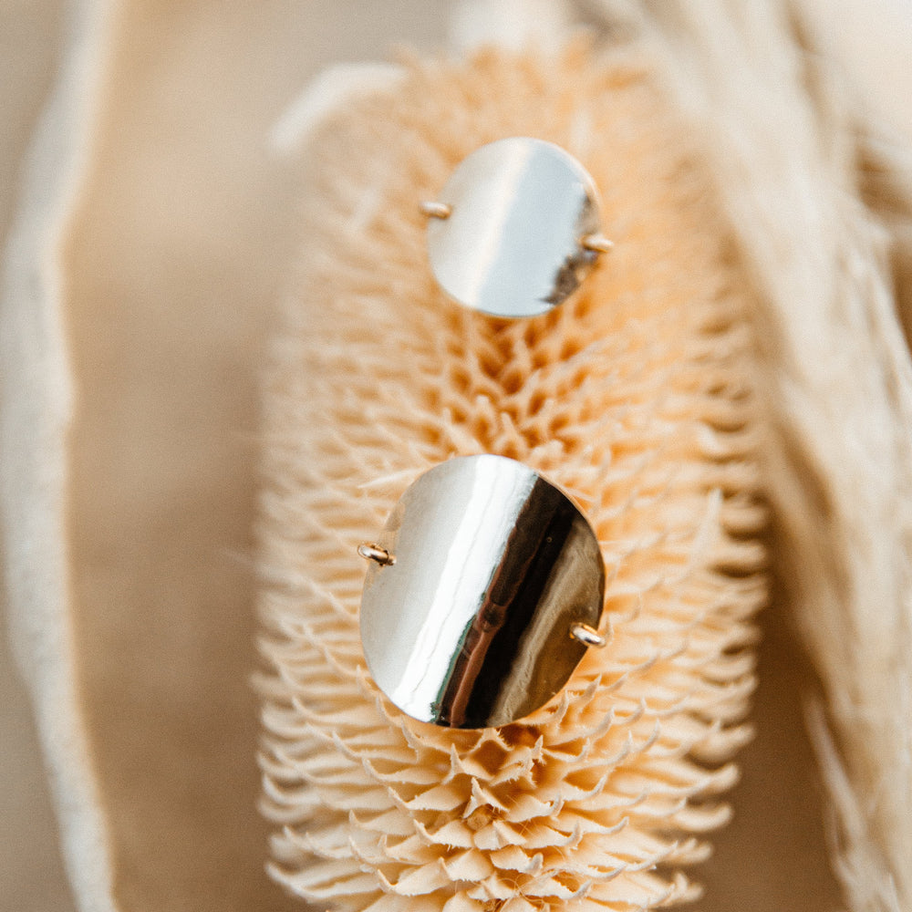 Silver disc rings on a textured beige surface