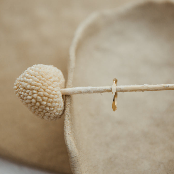 Close-up of gold diamond hammered gold ring on a blurred beige background