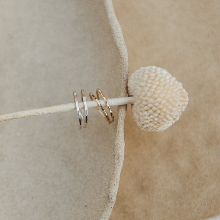 gold and silver wrap rings styled on wooden stick on a beige surface
