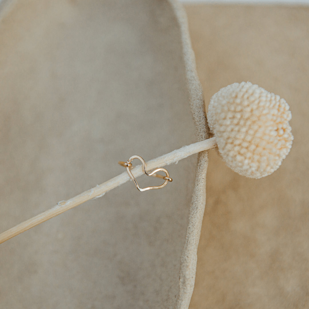 Gold heart-shaped earring on a beige background