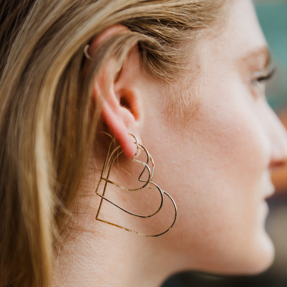 Close-up of a woman wearing a gold heart-shaped earring.