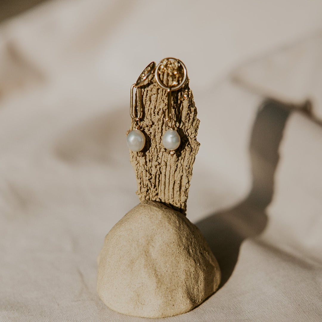 Wooden sculpture with spherical base and pearl-like beads on a neutral background