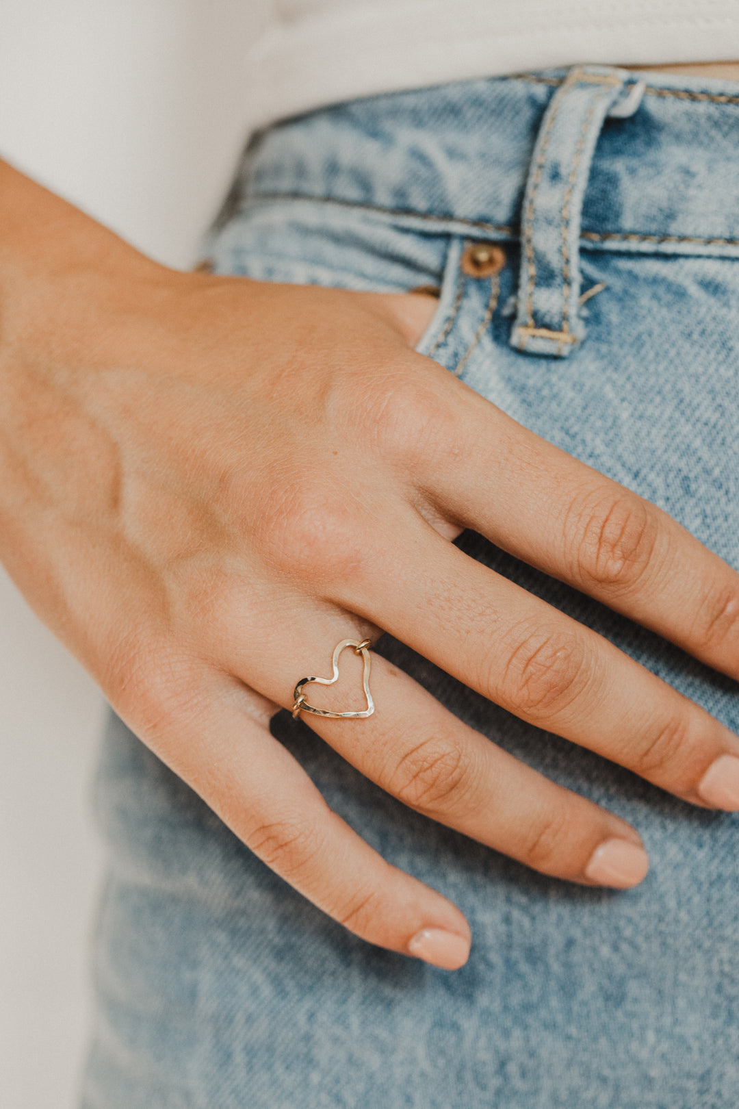 close up of hand wearing gold heart shaped hand made ring
