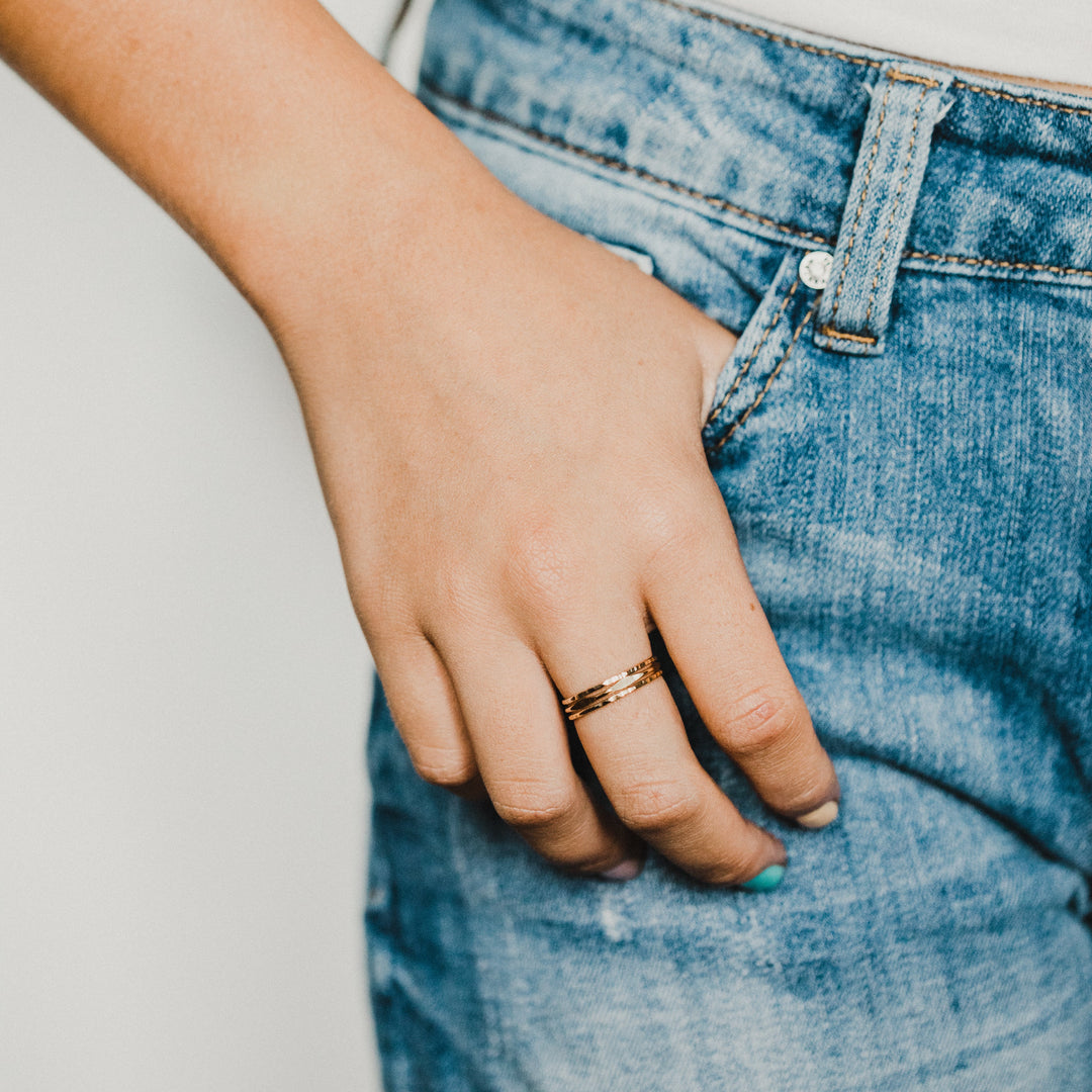 Hand wearing 3 gold rings on a blurred background