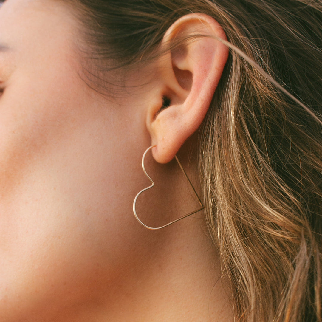 Close-up of a person wearing a gold hoop earring with a blurred background