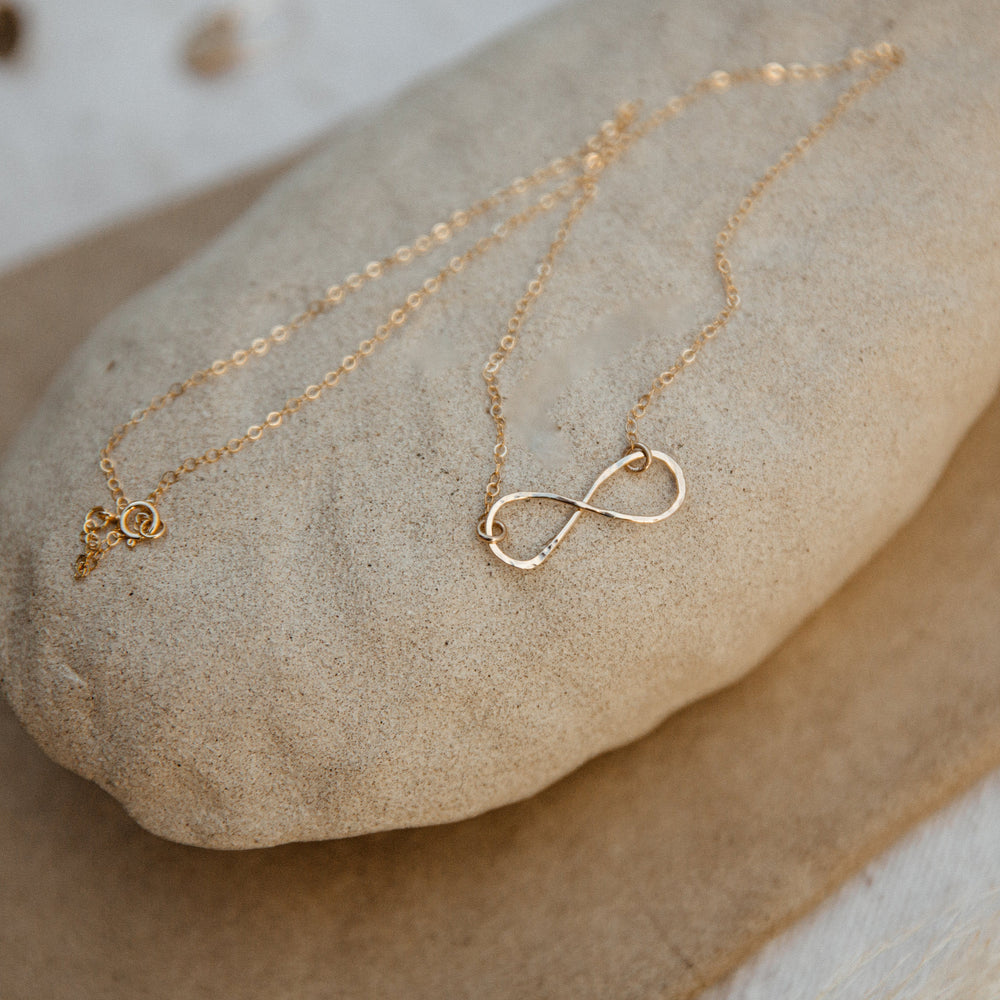 Gold necklaces with  infinity design on a stone surface