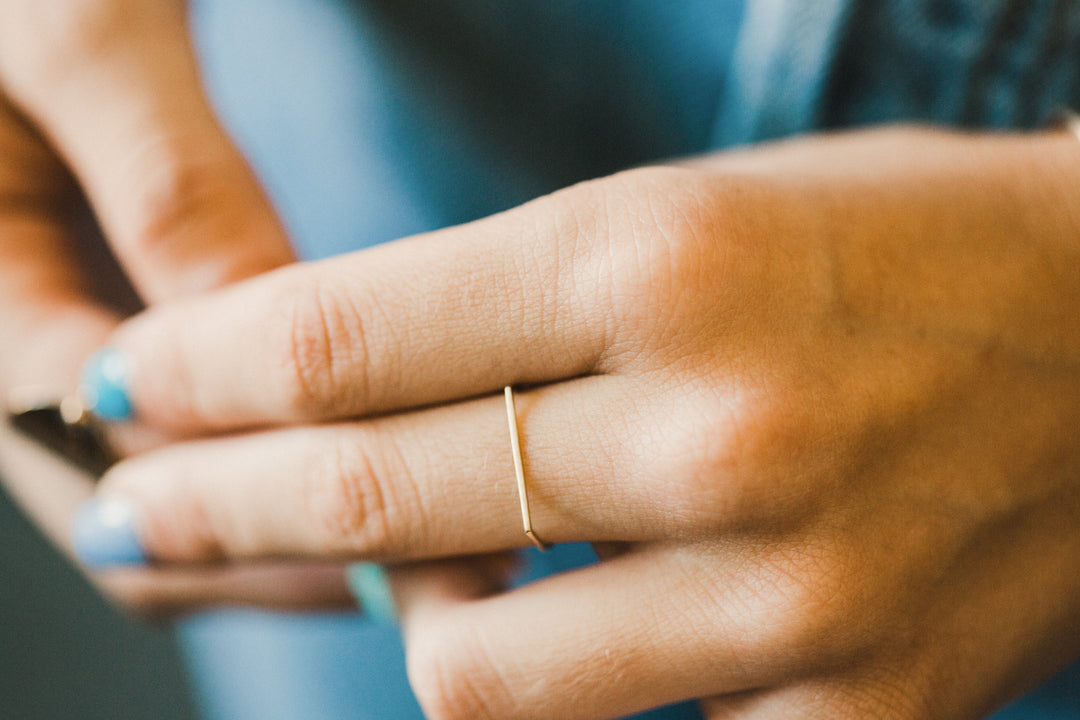 Close-up of a hand wearing a gold hand made ring with a blurred background