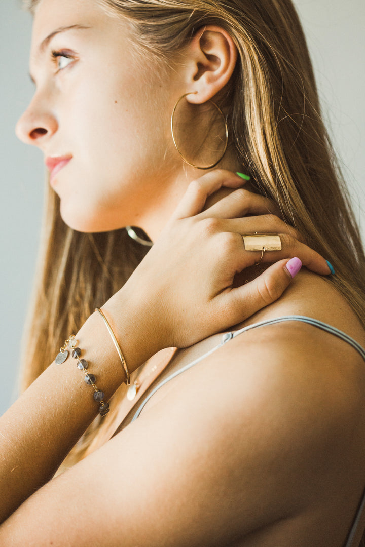 Woman wearing rectangular shield ring  with a neutral background