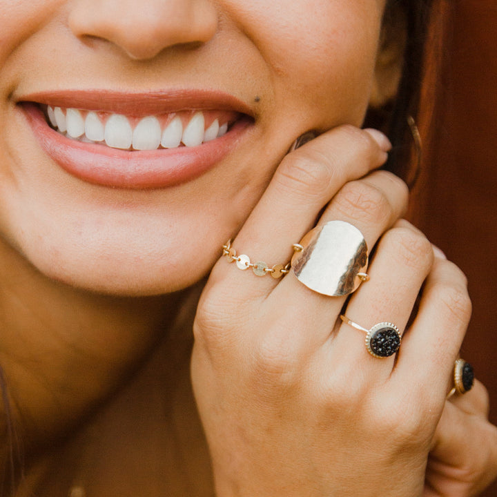 close up of hand with gold chain link ring with women with big smile