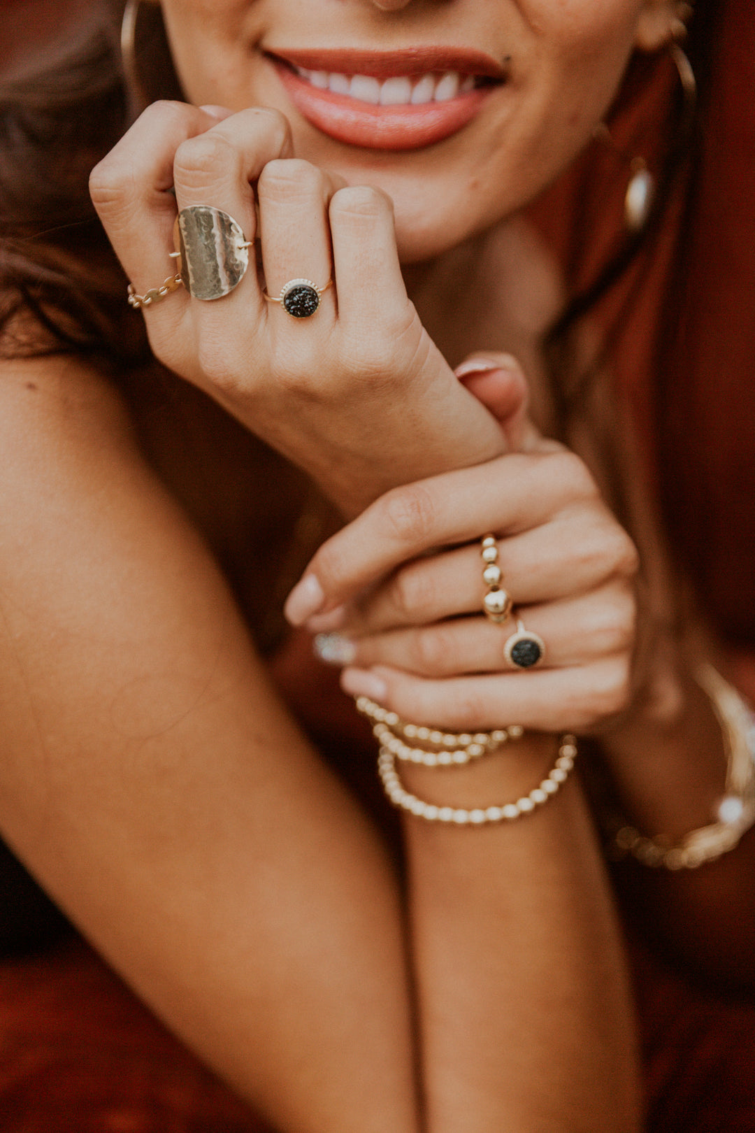Close-up of a woman's hands with multiple black druzy gem gold rings 