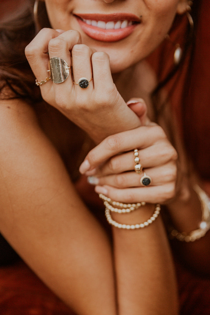 Close-up of a woman's hands with multiple black druzy gem gold rings 