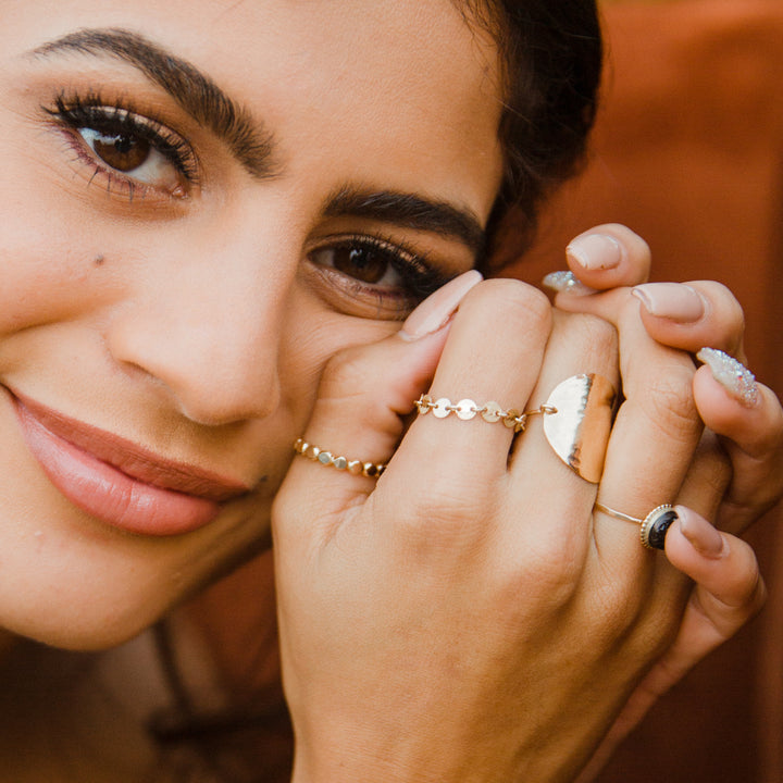 close up of hand with gold chain link ring 