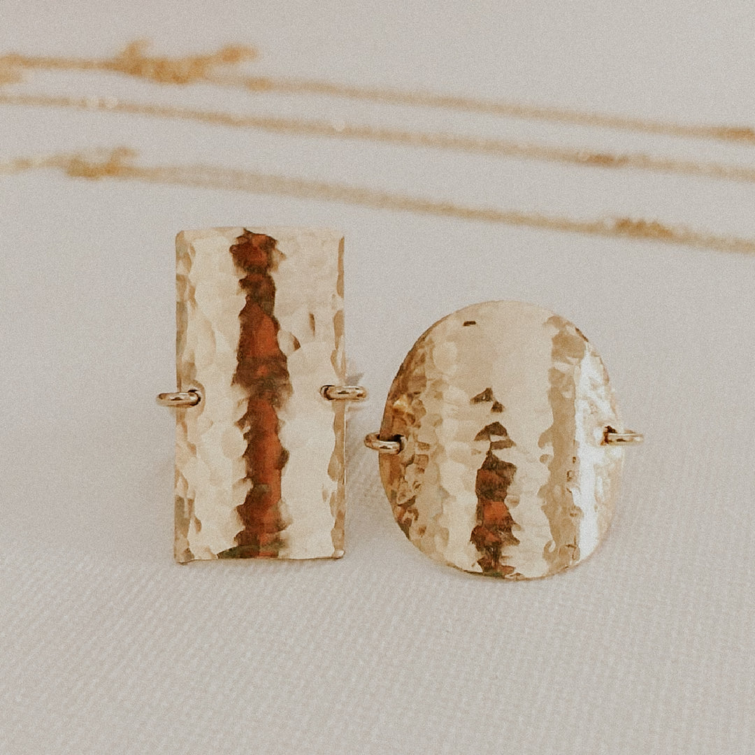 gold rectangular ring
 with textured surfaces on a light background
