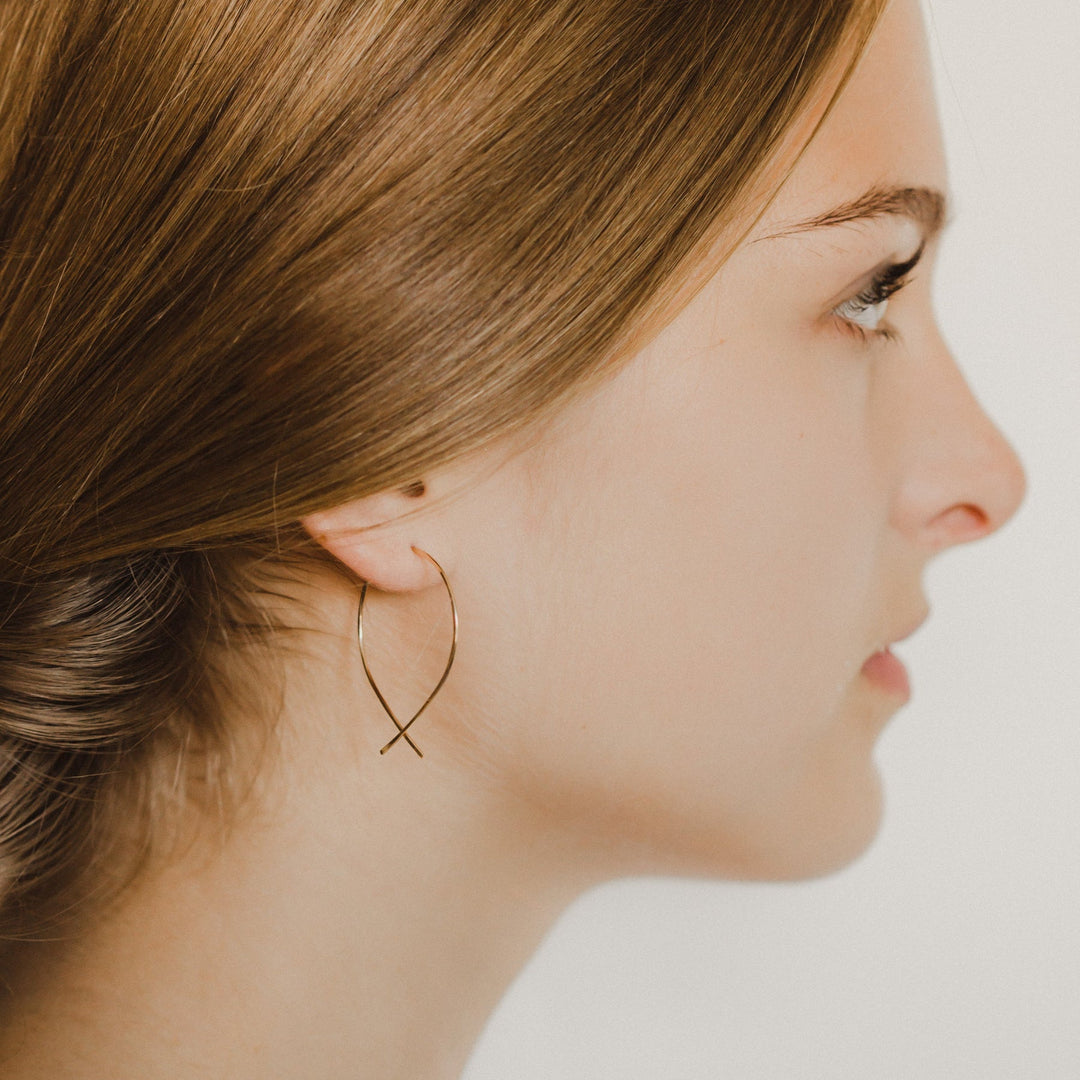 Profile of a woman wearing a gold hoop earring against a neutral background