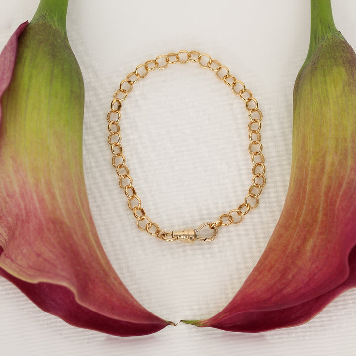 Amelia bracelet in substantial 14k gold filled rolo chain with a vintage swivel clasp, laid flat between pink calla lilies