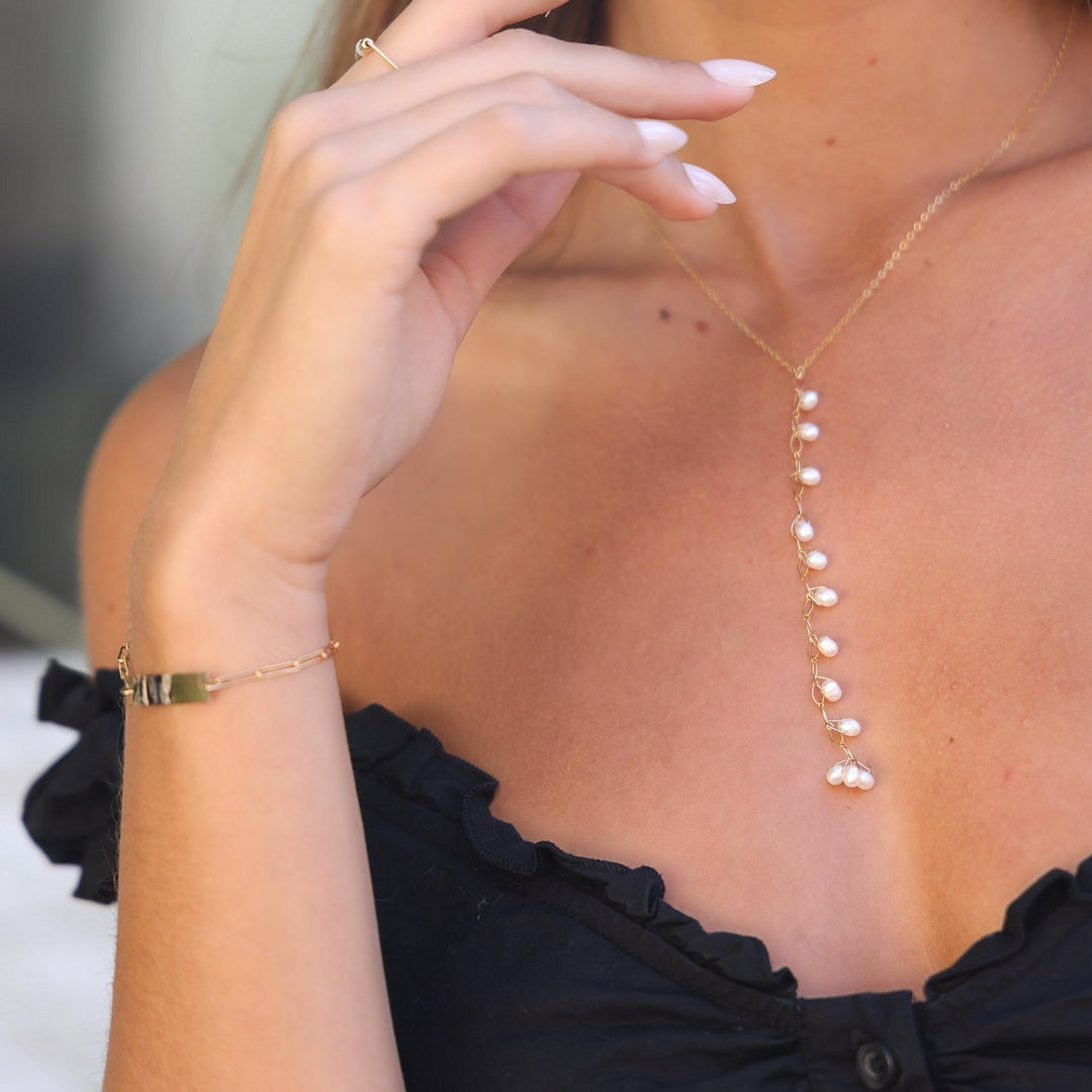 Model wearing the gold filled Celeste pearl Y-drop necklace with pearl hoops and a gold bar bracelet