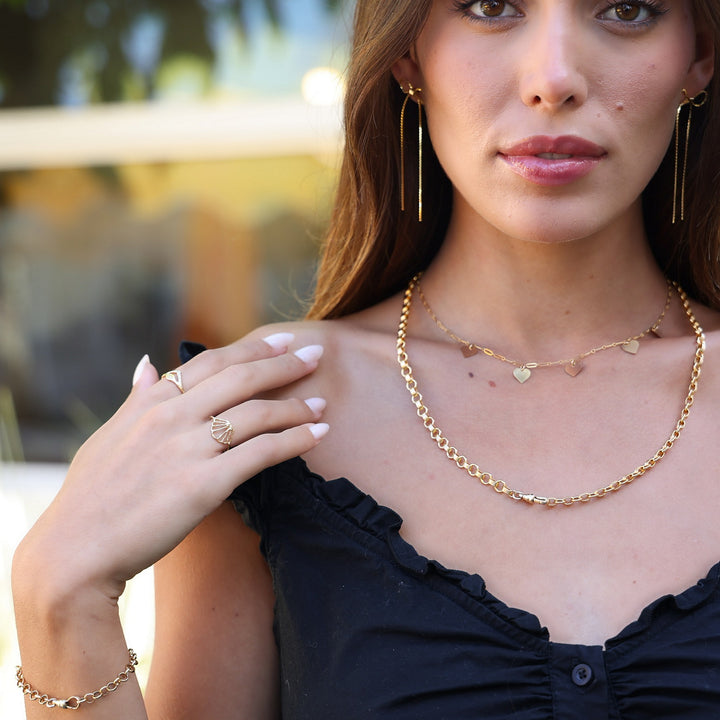 Model in a black ruffled top wearing Long Dangle Coco Bow Earrings with layered gold necklaces