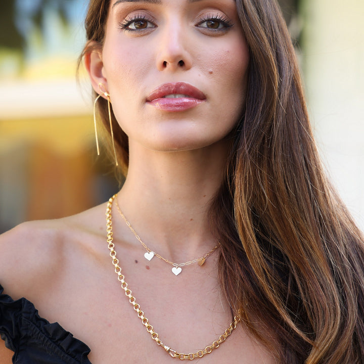 Model with her head turned wearing the Long Dangle Coco Bow Earring and layered gold necklaces