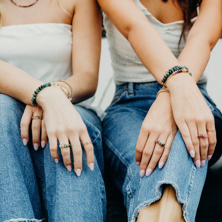 Two women displaying Diane Bracelet gemstone jewelry on their wrists, showcasing vibrant colors and stylish designs