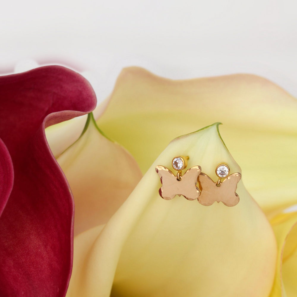Dolly earrings, hammered edge gold filled butterflies dangling from cubic zirconia posts, set on a cream calla lily