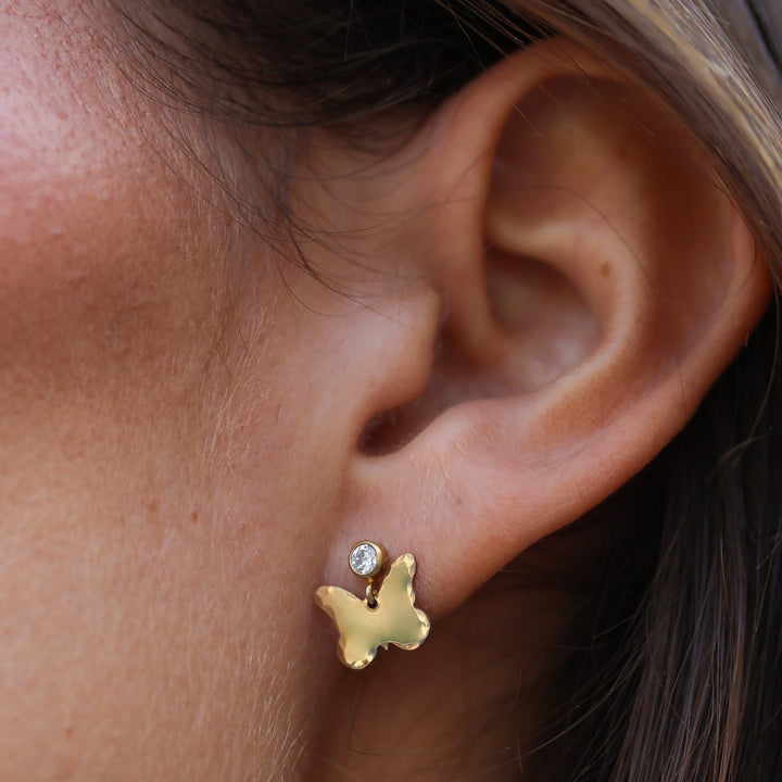 Close-up of a Dolly butterfly earring on the ear, cubic zirconia post above a hammered gold filled butterfly