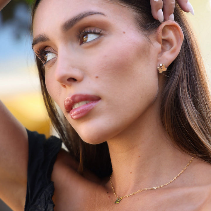 Model wearing the matching Dolly butterfly earrings and necklace, hand resting in her hair