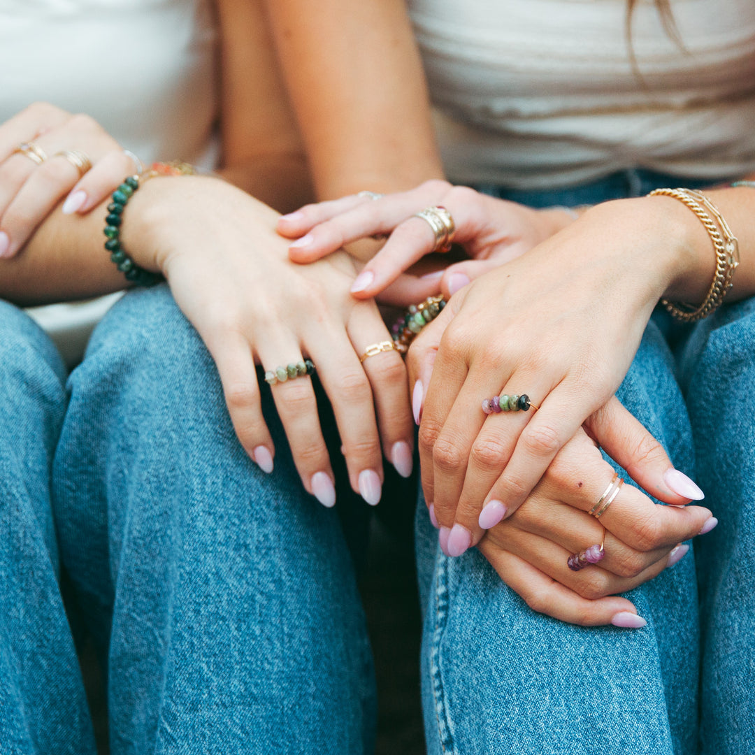 Two women showcasing various rings including the Emma gemstone ring on their hands, with stylish nail polish