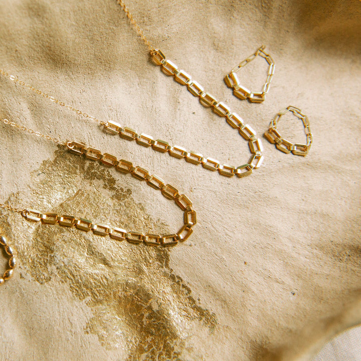 Elegant handmade jewelry Carlsbad featuring gold rings, necklace, and earrings on a neutral background